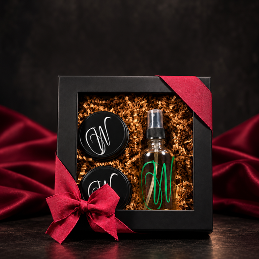 The Sensual Suspects gift bundle by Wiick'd Candle Company, featuring two mini tin candles and a 4 oz Room & Linen Sprayin a black gift box with ribbon.